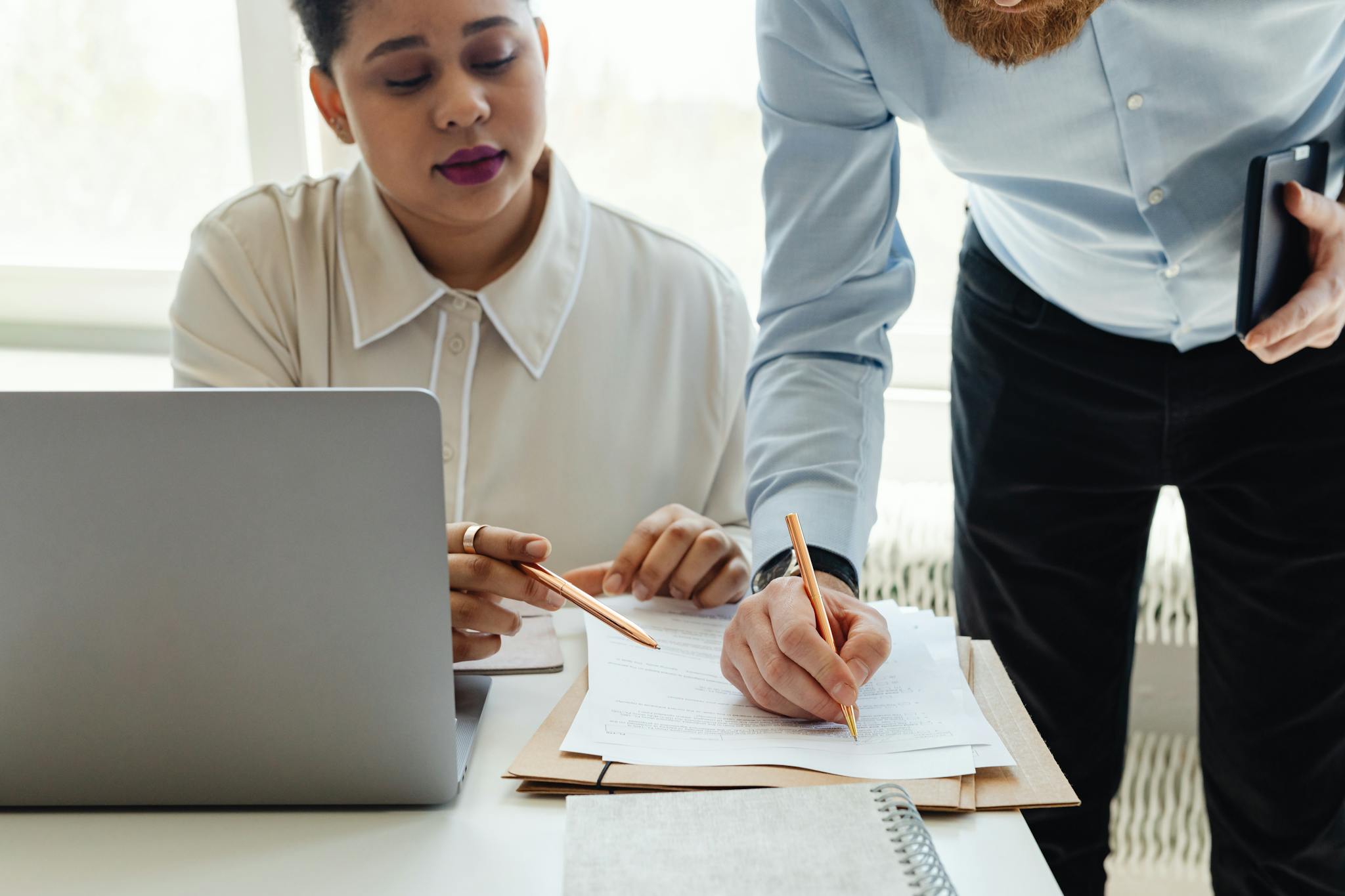 Two colleagues collaborate on paperwork during an office meeting.